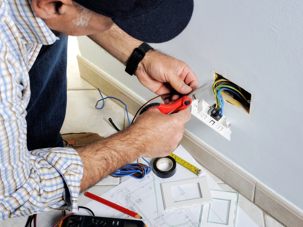 Electrician stripping the cable to connect switches and sockets of a residential electrical installation